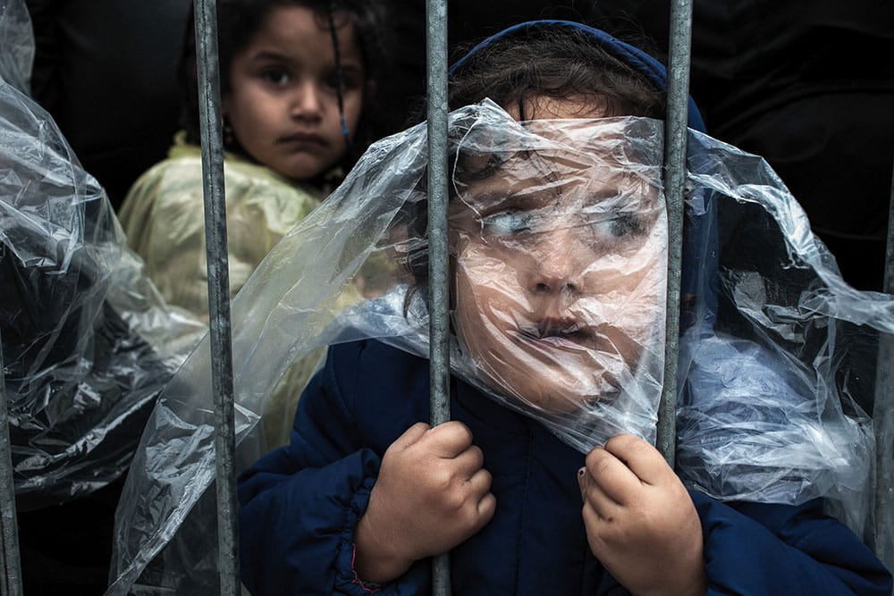 © Matic Zorman, Waiting to Register. PRESEVO, SERBIA - OCTOBER 7, 2015: A child refugee is covered with raincoat while she waits in line to get registered in Presevo refugee registration camp. Most of the refugees who crossed Serbia try to continue their route towards Hungary, Croatia, Slovenia and other countries of the European Union.