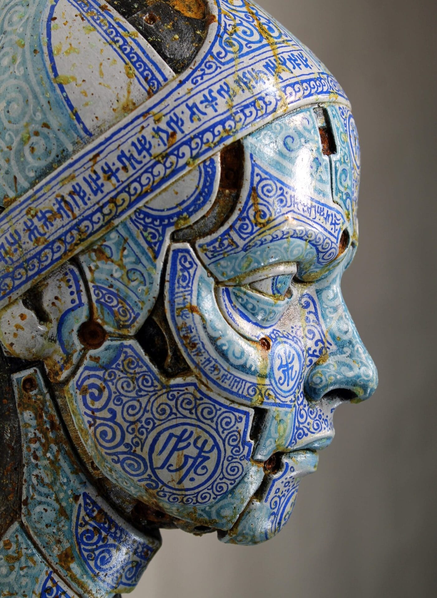 a weathered figurative sculpture made of cracked blue and white tiles
