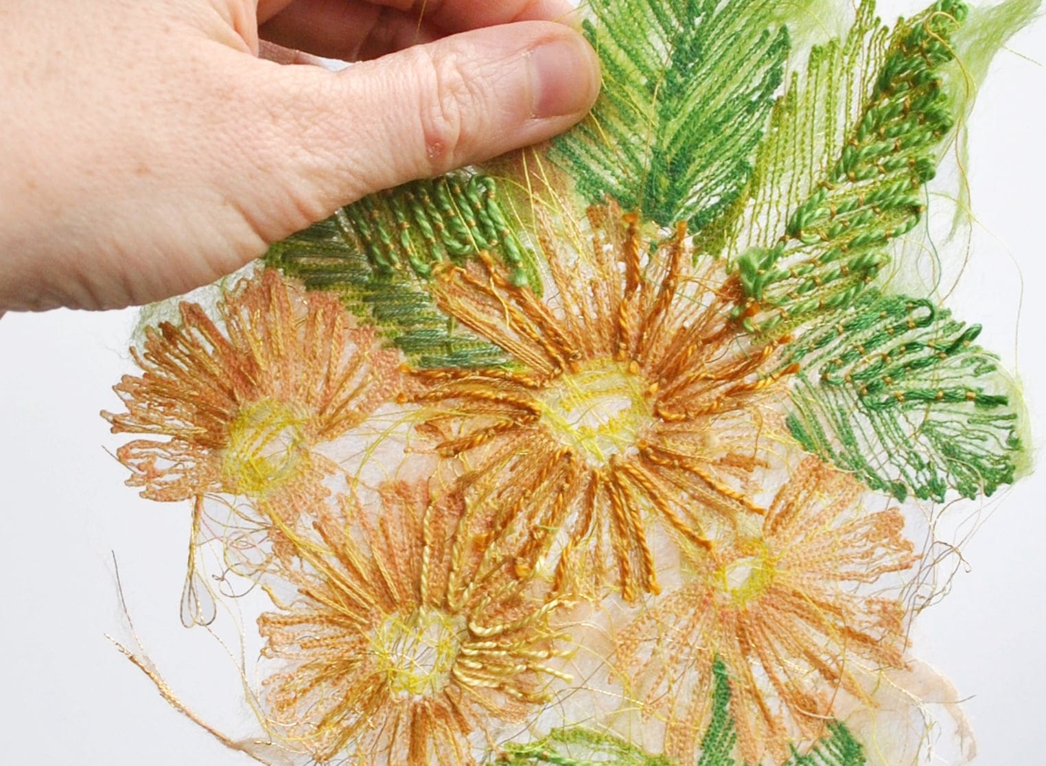 A photo of a hand holding an embroidered flower
