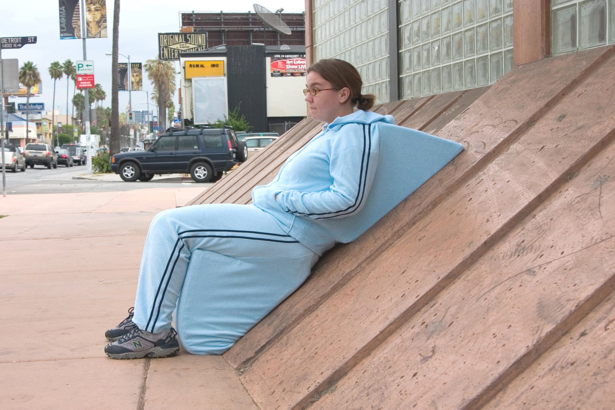 a woman in a suit rests on a sidewalk