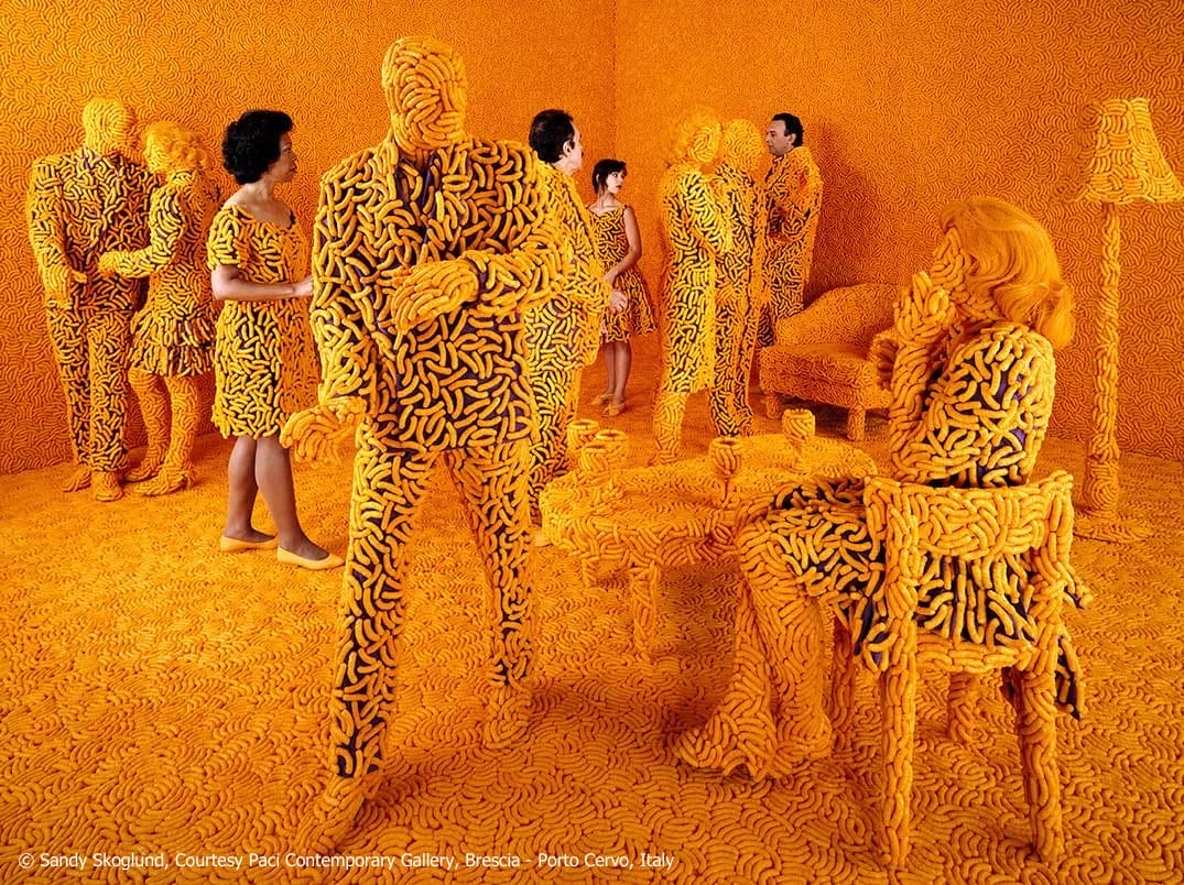A photograph by Sandy Skoglund of a cocktail party in a set where everyone and everything is covered in Cheetos.