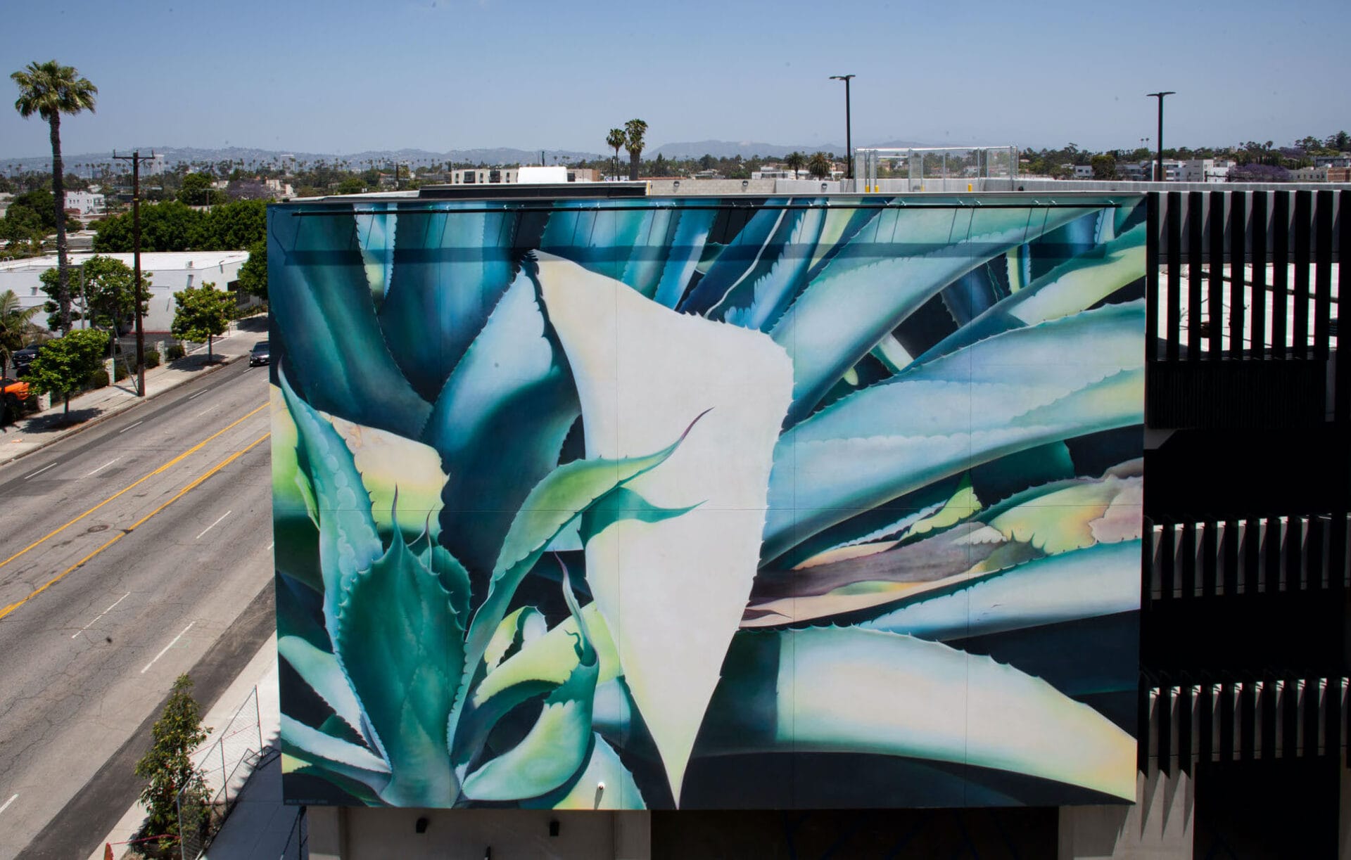 the side of a building covered in a mural of green leaves