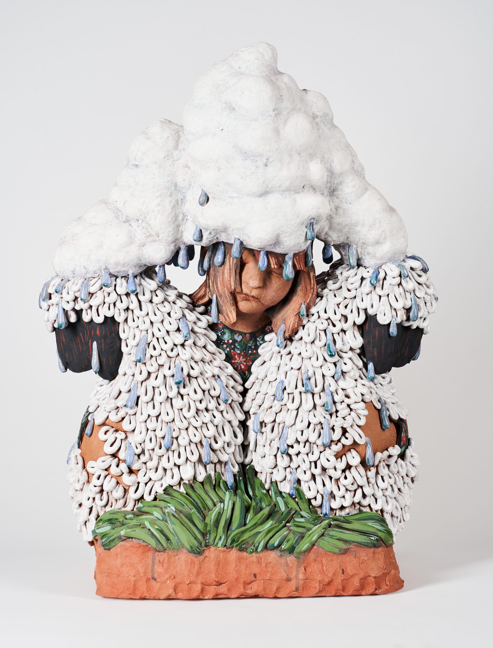a ceramic sculpture of a young girl embracing two lambs. a cloud looms above her head, with teardrops emerging from the bottom of it