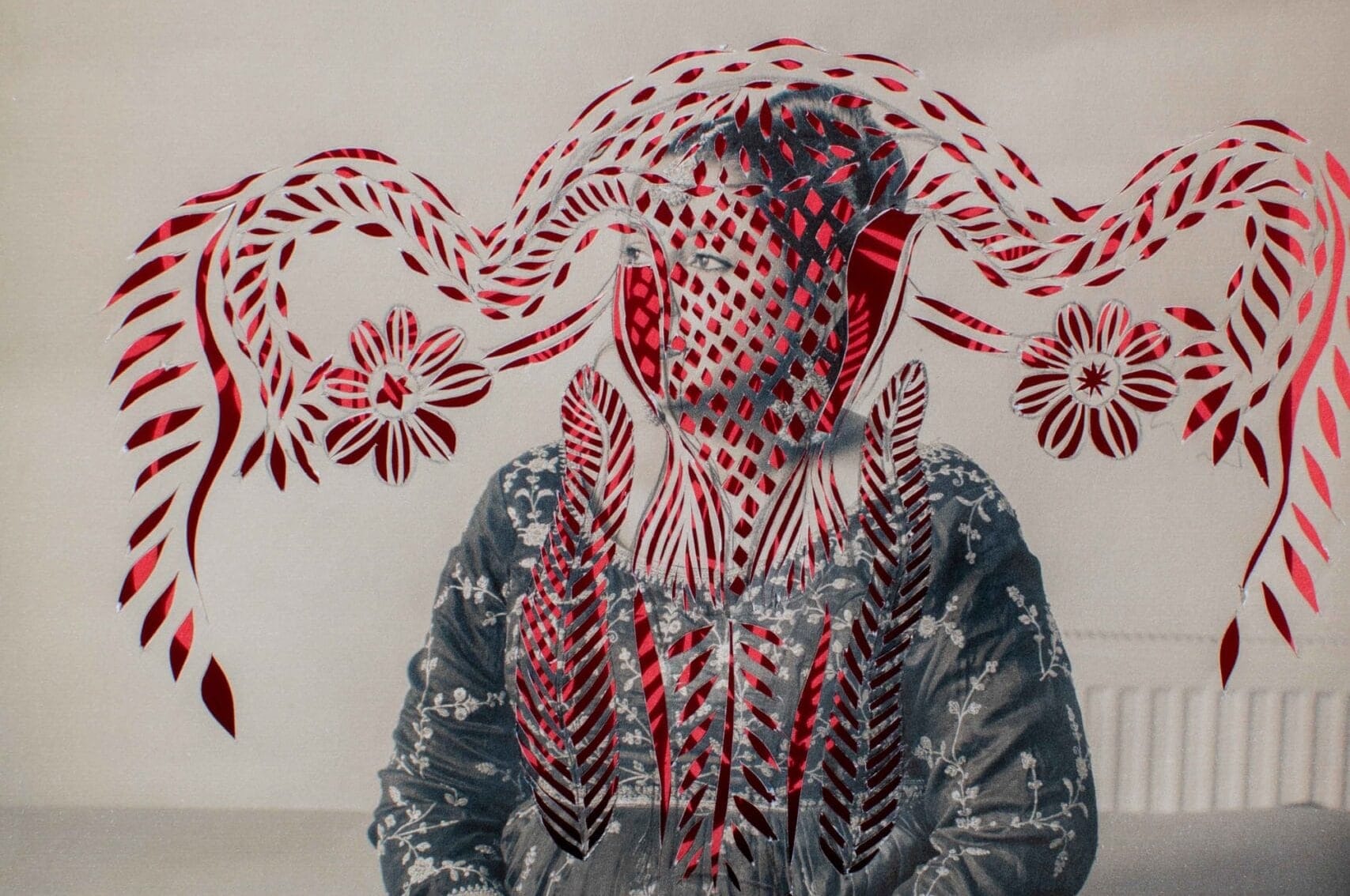 a black-and-white photograph of an anonymous south Asian woman that has been cut with a pattern in the outline of a uterus, with red paper shows through from the back