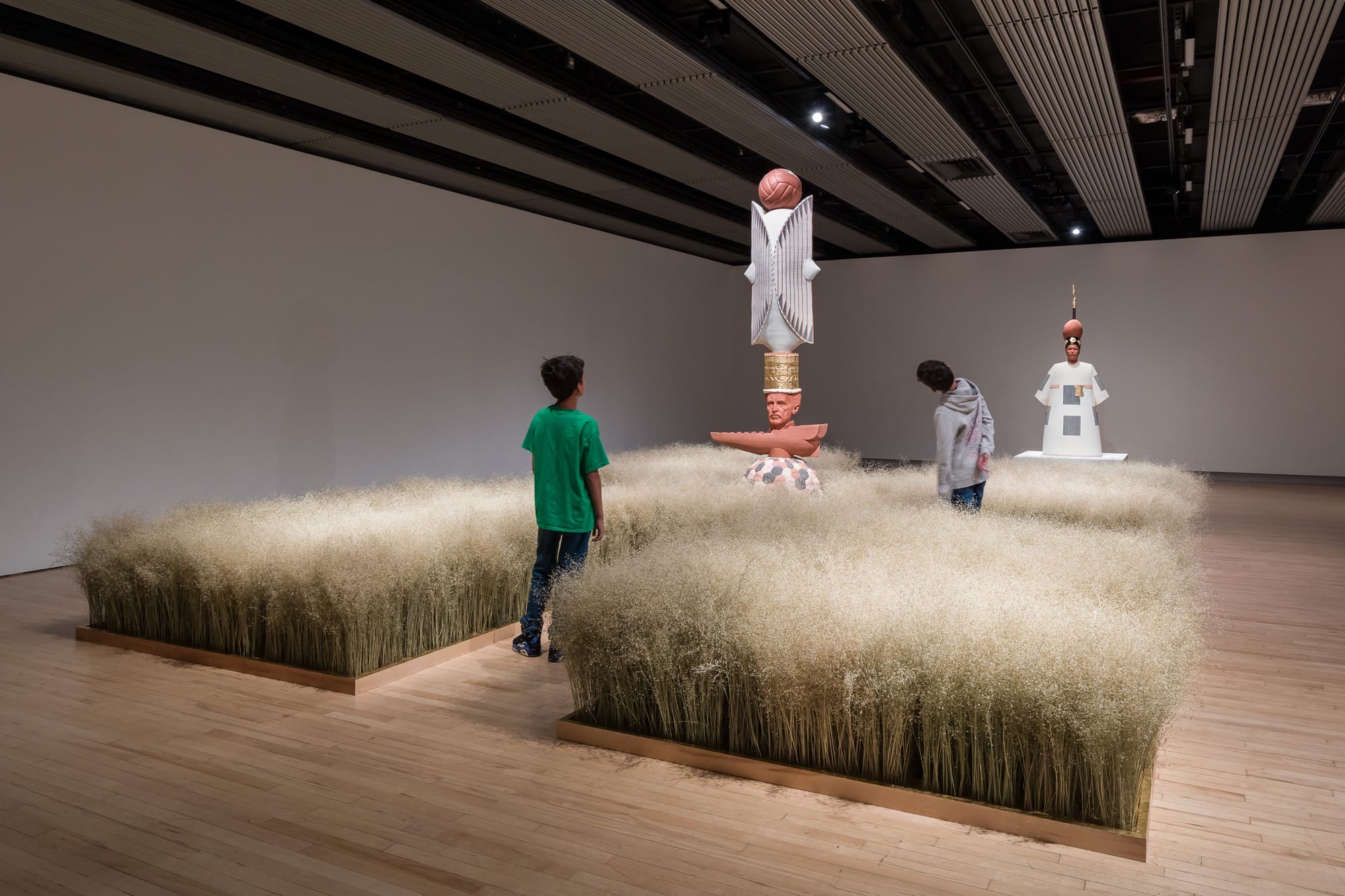 an art installation featuring rice in quadrants and totem-like sculptures in the middle of the room