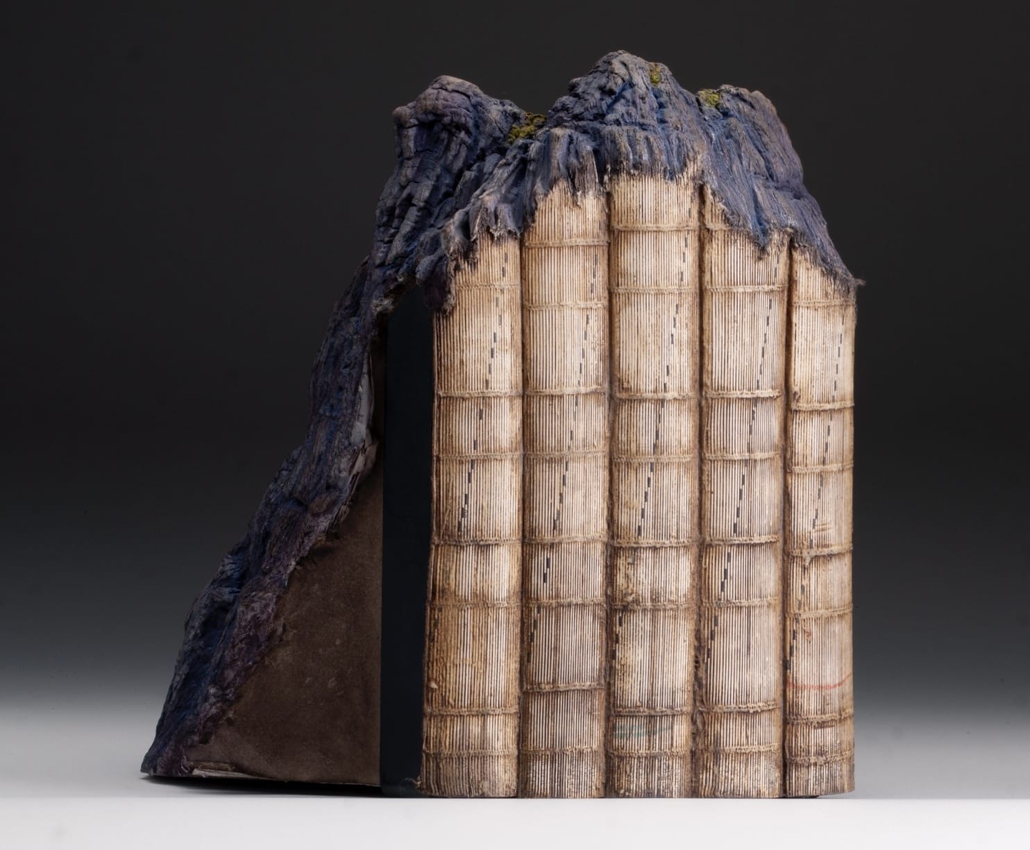 a sculpture made from a set of large books, covers removed to reveal the stitched binding, which has been water-blasted to soften and manipulate the pages into a form resembling a large mountain