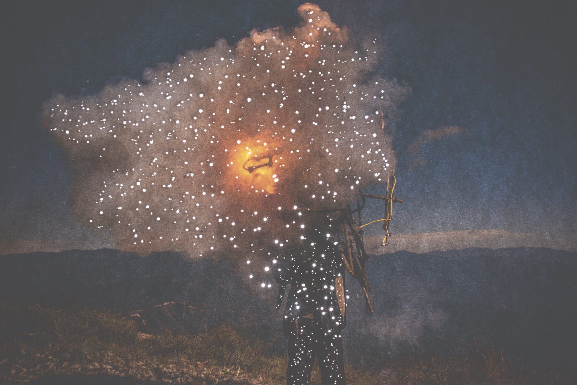 small holes pierce a dark photo of a person holding fire