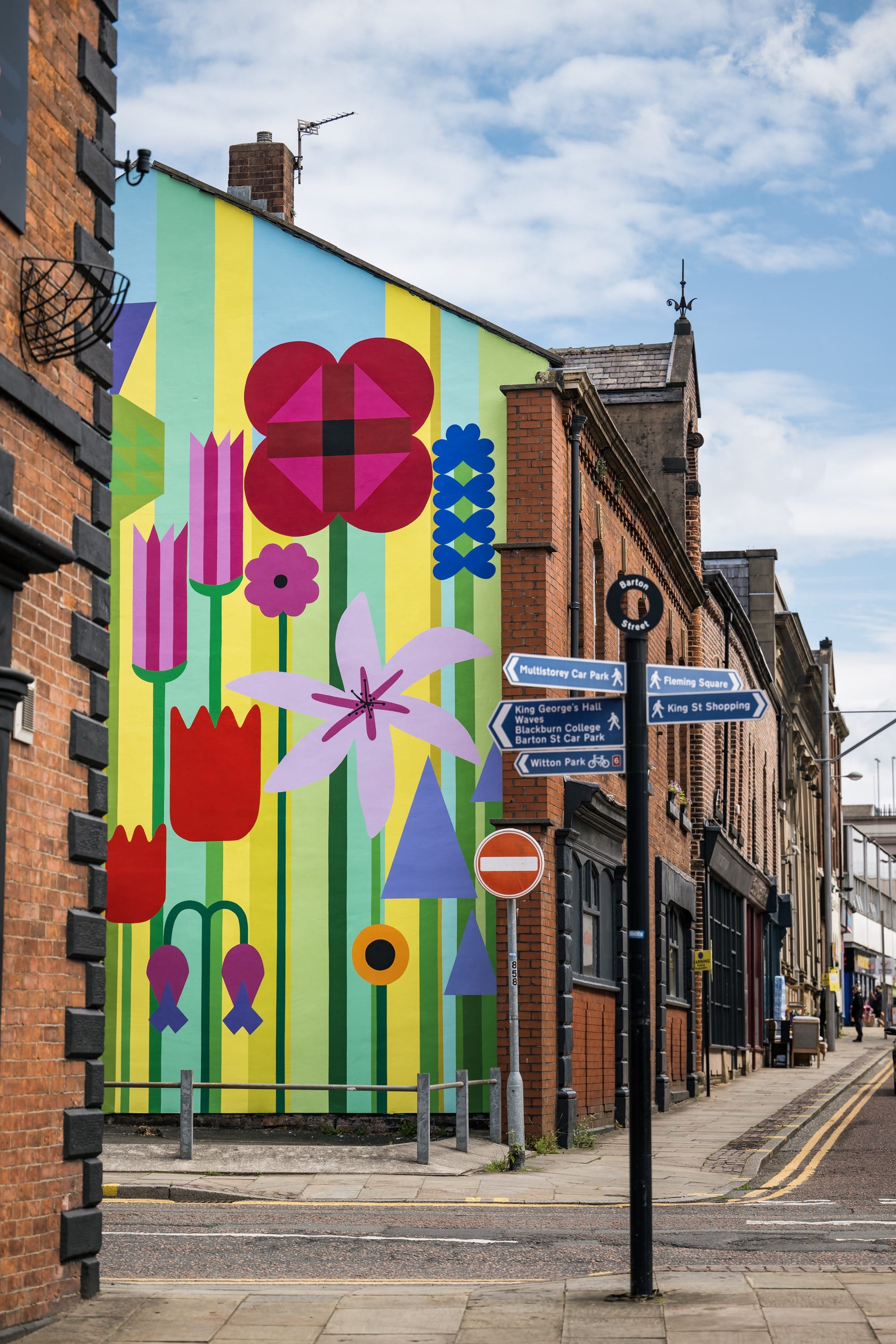 a brightly colored floral mural on a brick building in a small downtown area