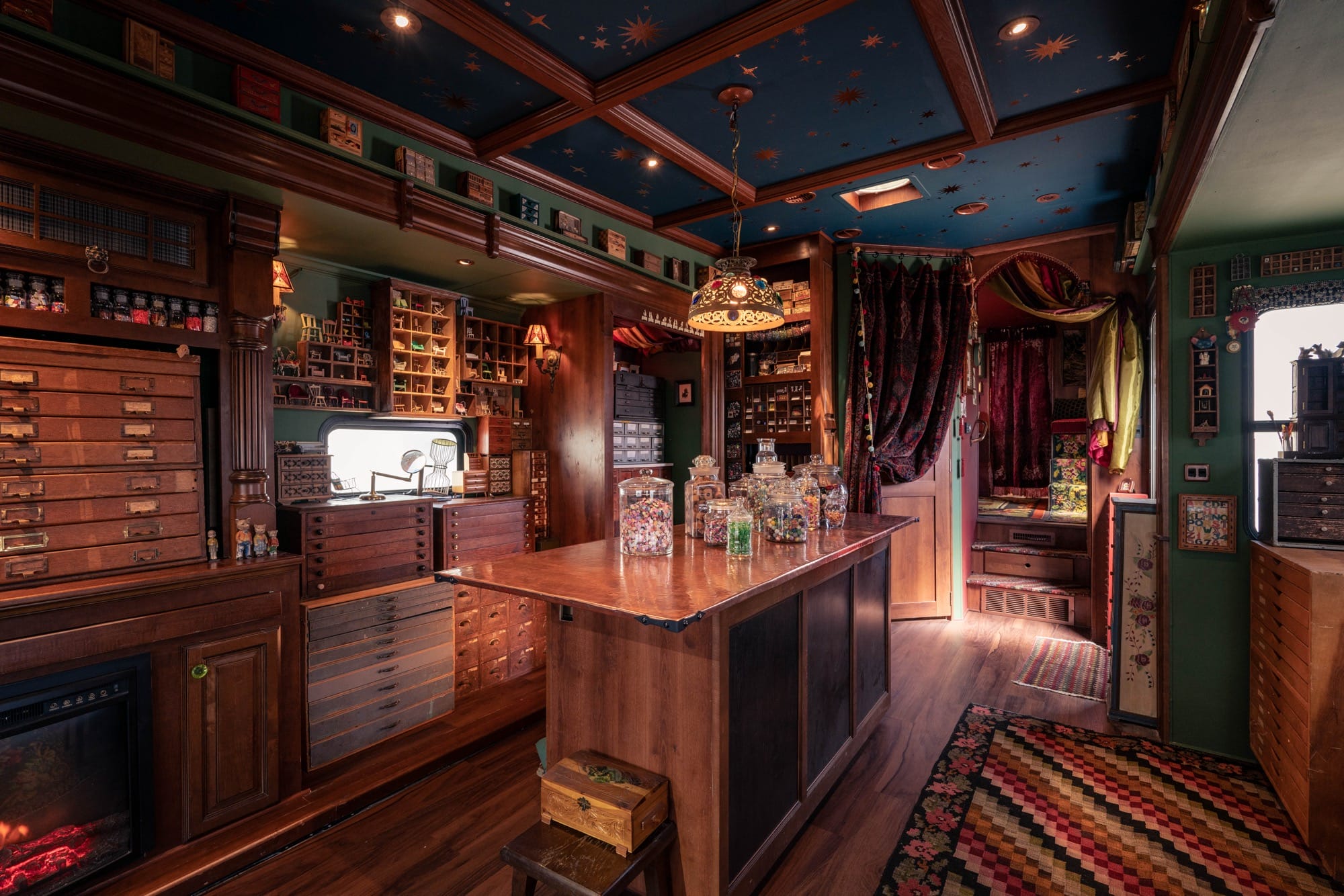 the moody wood and soft seating interior of a traveling museum with cabinets, jars, and lots of storage