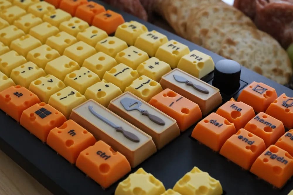 a part of a keyboard with key covers shaped like cheese and a charcuterie board