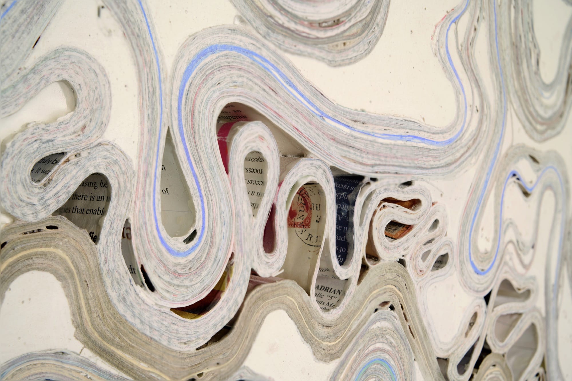 a detail of an abstract wall artwork by Jessica Drenk using repurposed junk mail and plaster in curving forms