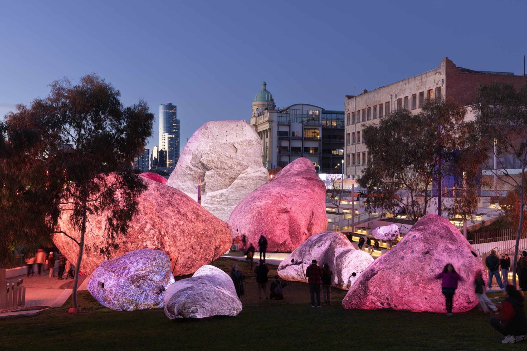 people stand between massive inflatable rocks glowing in pinks