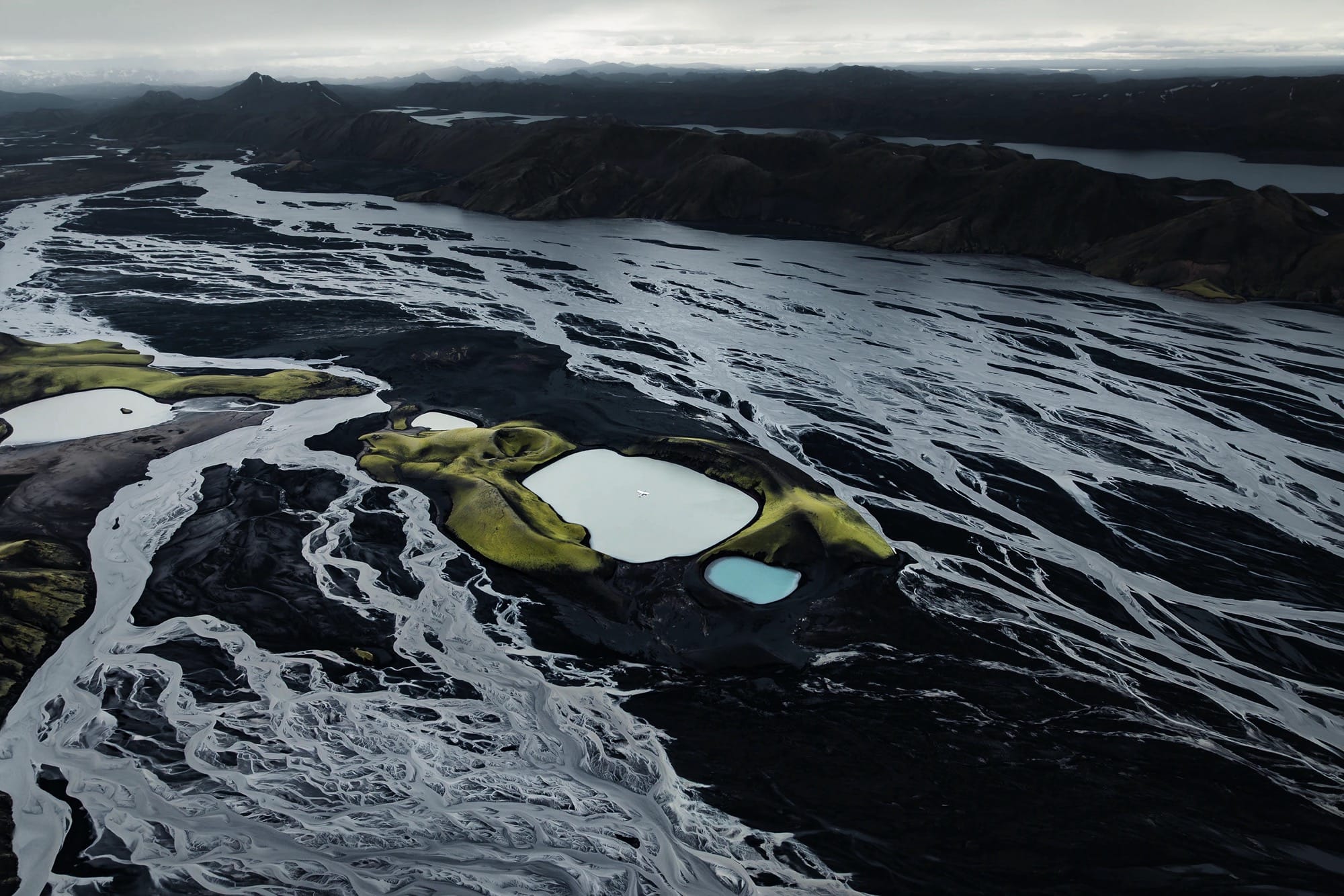 a dramatic Iceland landscape photographed from the air by Dani Guindo showing rivers, a glacial lake, and a tiny plane
