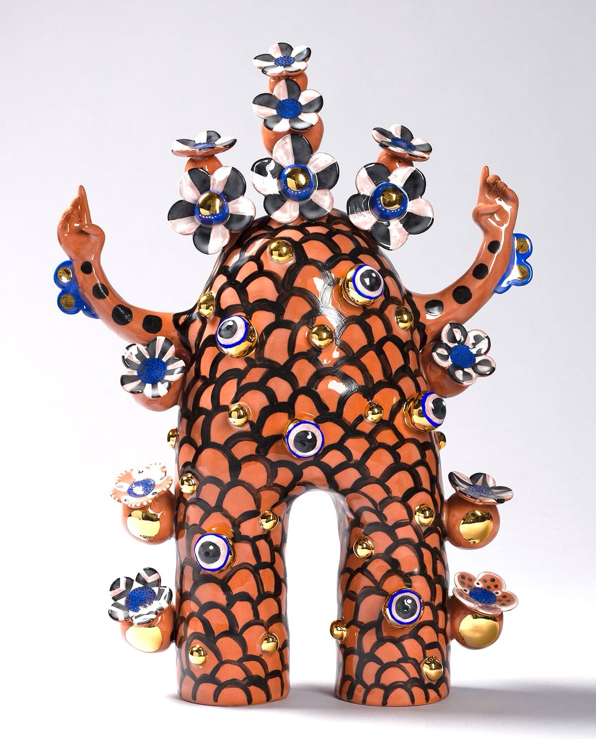 a terracotta figure with flowered patterns and peace sign hands