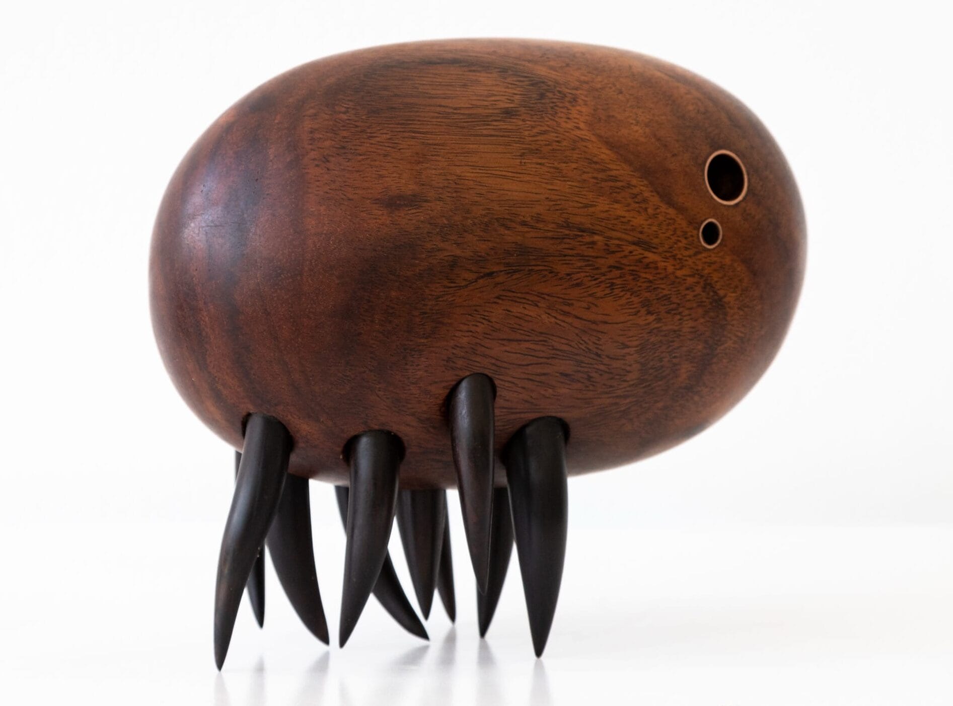 a wooden sculpture by Donald Wasswa with an abstract, sea creature-like form with short, black tentacles