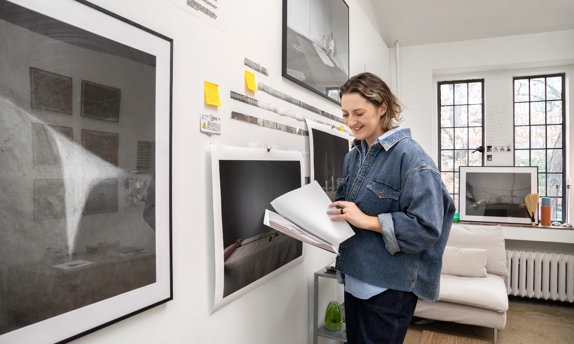 Person holing papers in front of framed photographic artworks.