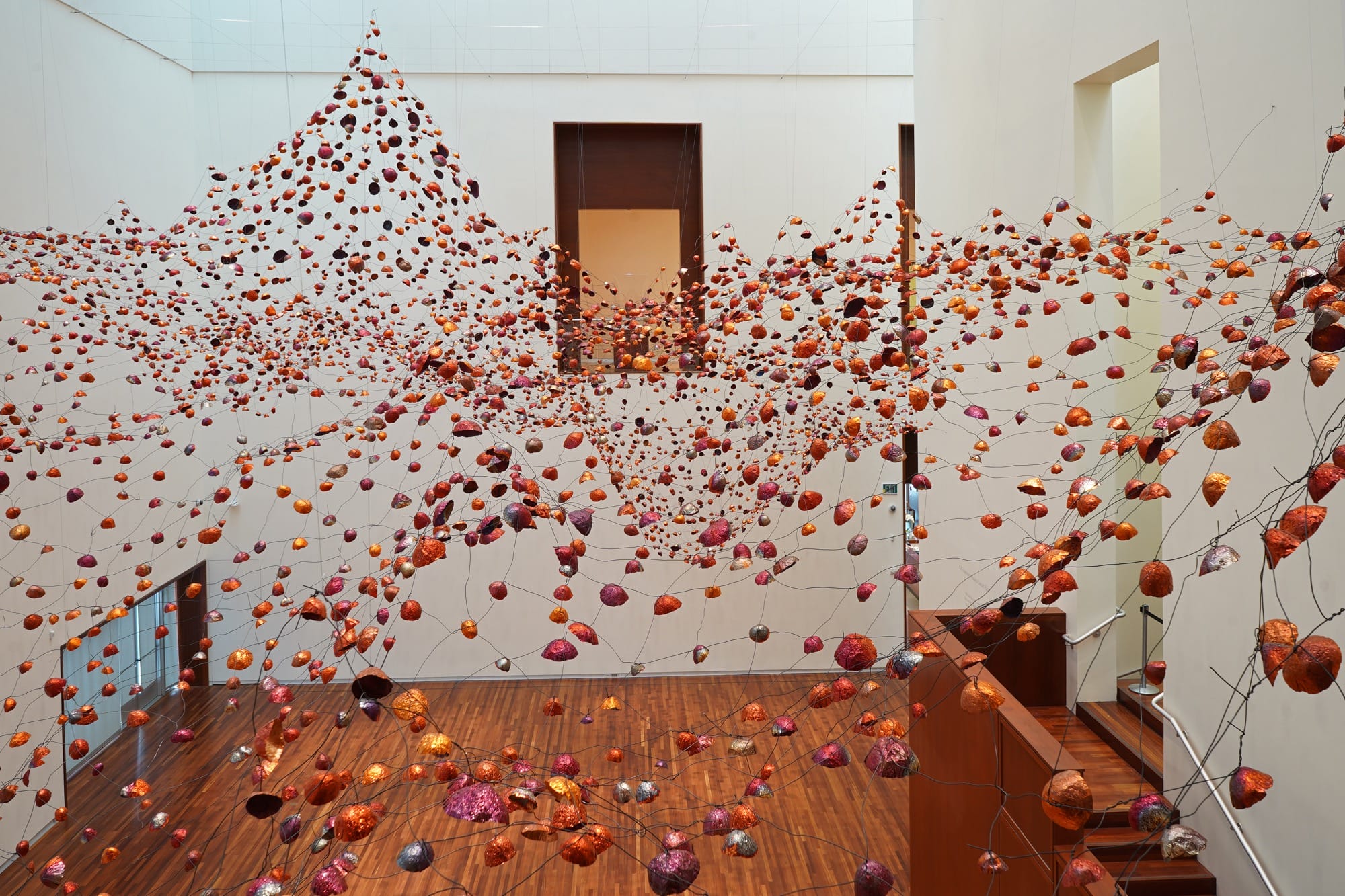 an installation view of a room-size installation by Yasuaki Onishi made of hundreds of copper forms connected by wire