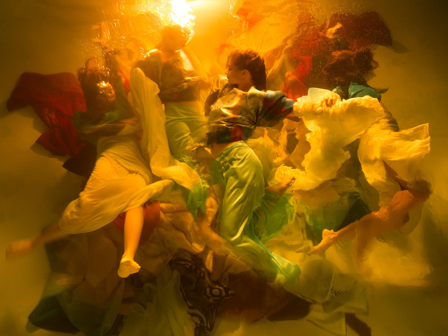 an underwater photograph by Christy Lee Rogers of figures enveloped in billowing fabric