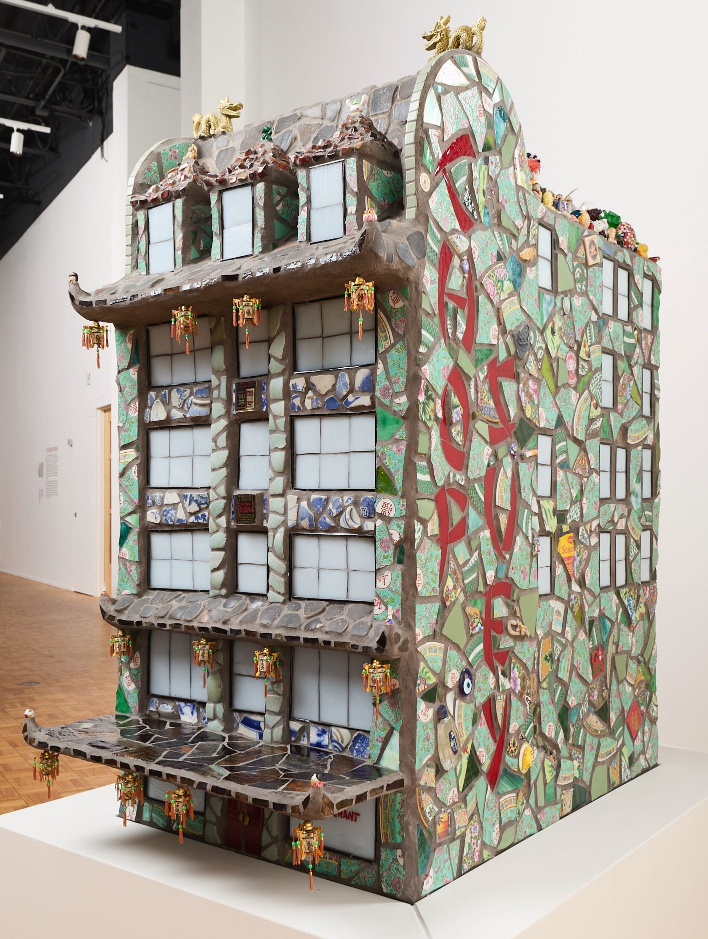a large building sculpture with mosaic sides and knick-knacks embedded throughout and covering the roof