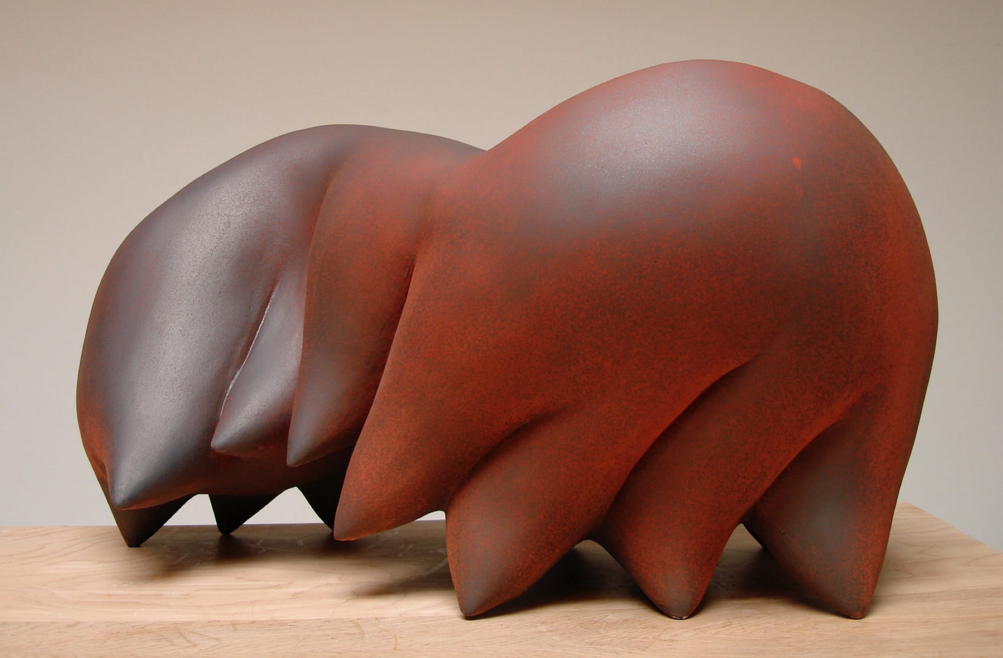 An abstract ceramic sculpture by Syd Carpenter of a bulbous reddish form