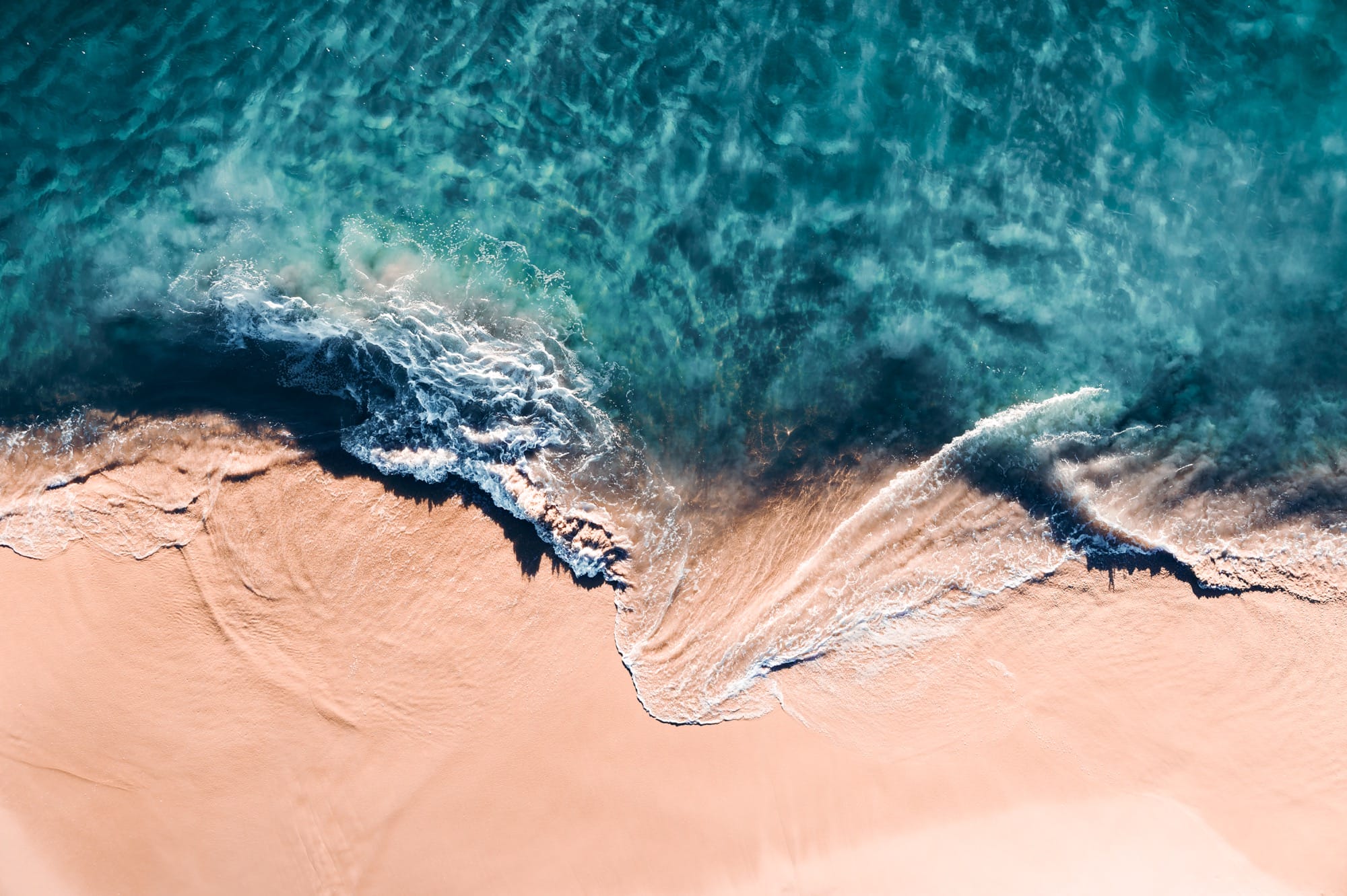 An aerial view of crashing waves shot at a vertical angle by Kevin Krautgartner
