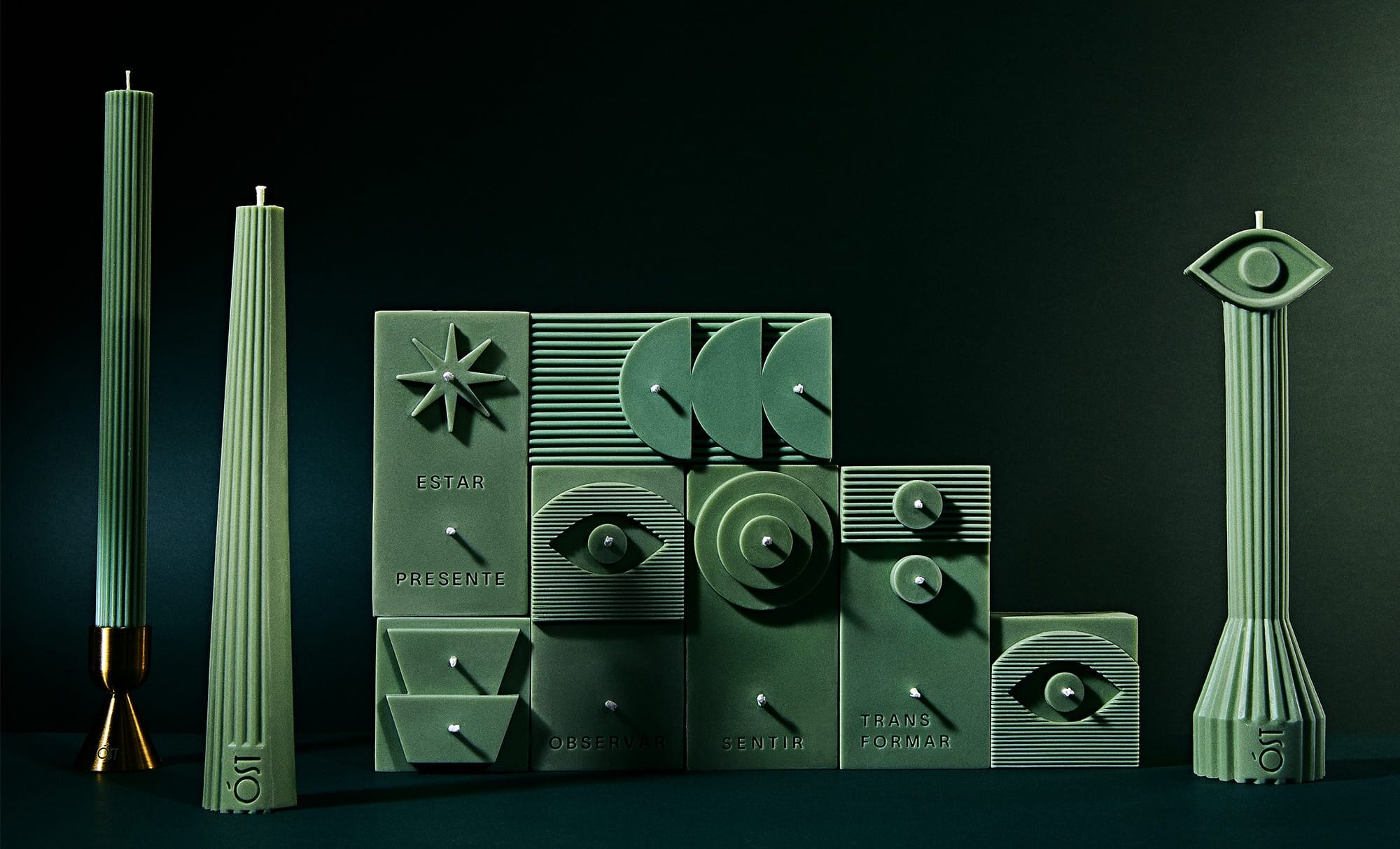 A series of green, geometric designer candles against a black background