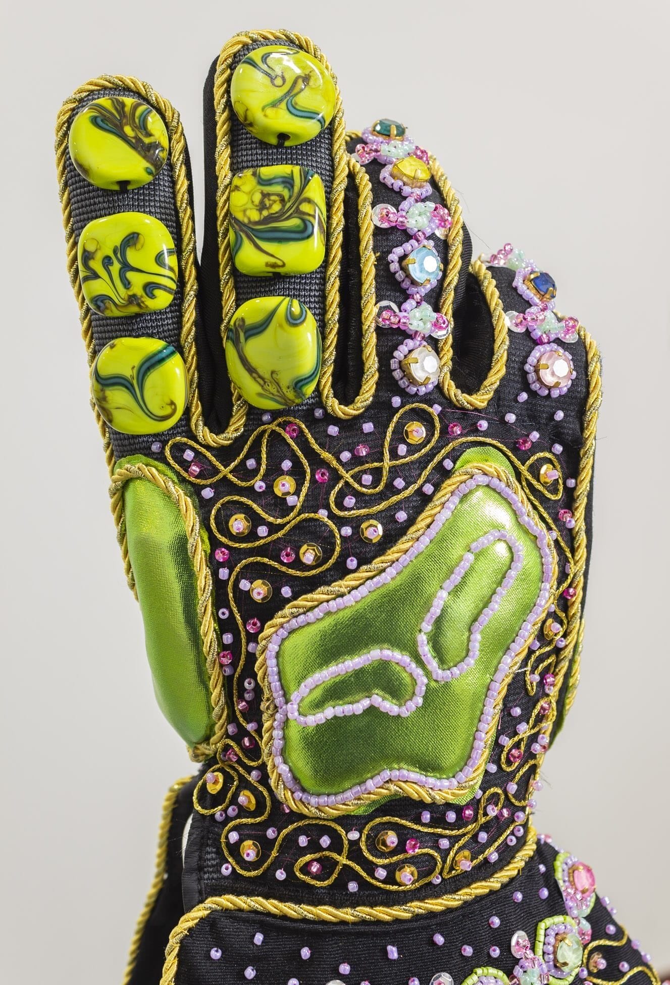 A detail of a sculpture by Jorge Mañes Rubio of a motocross glove embellished with beads and gold cord