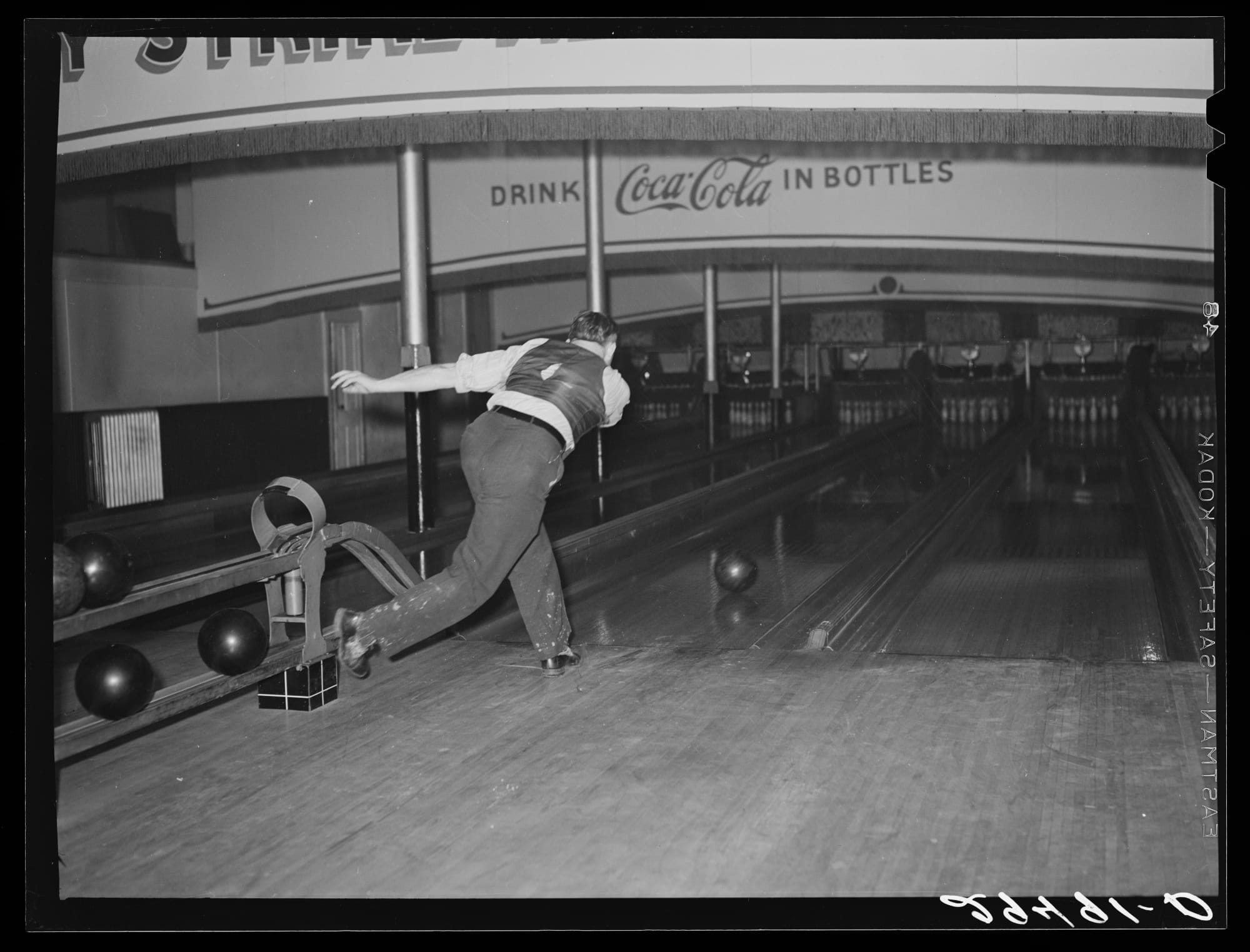a black and white photo of a man bowling by himself