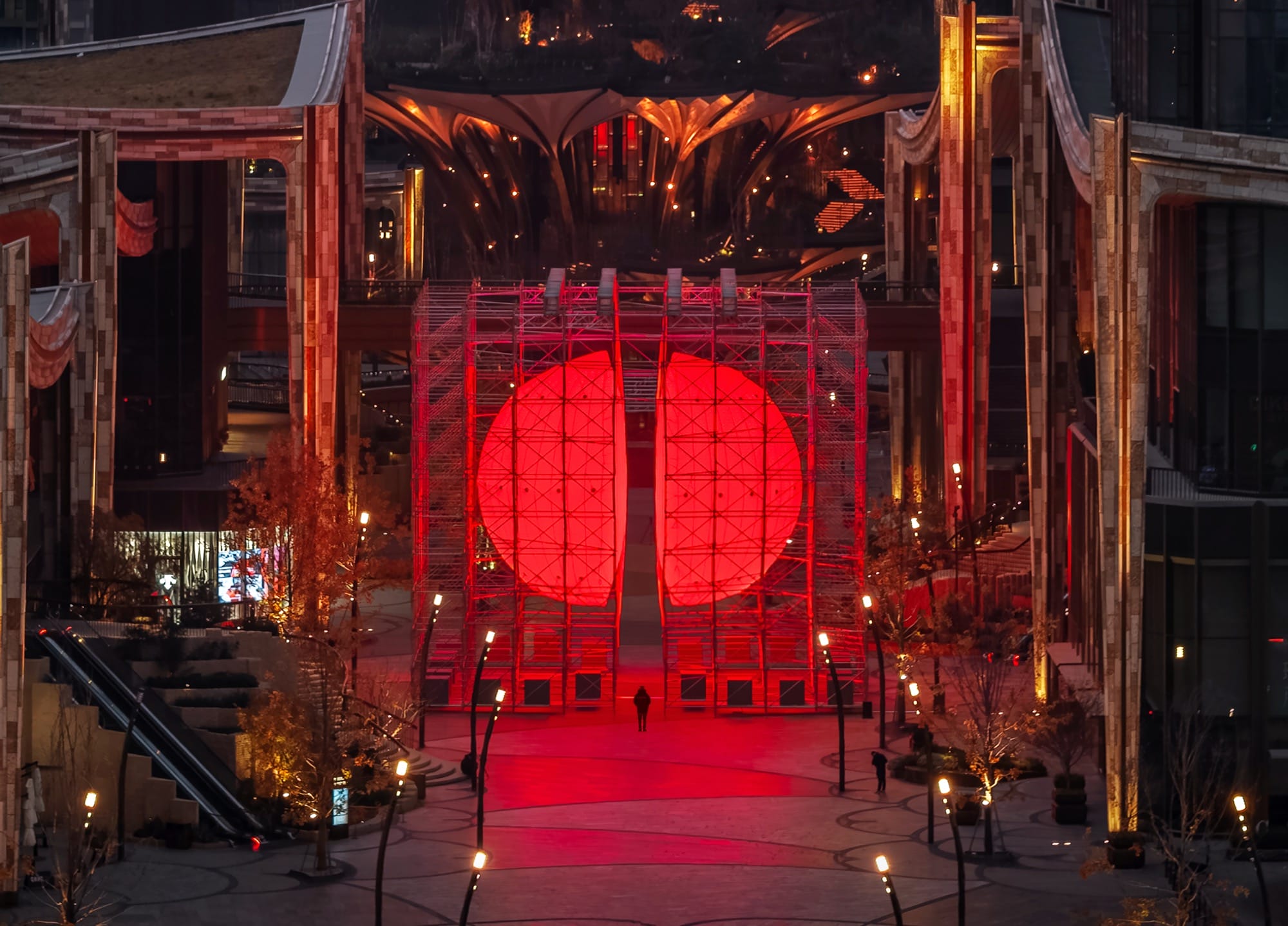 A large-scale installation by SpY of two glowing, red half-spheres within a metal framework