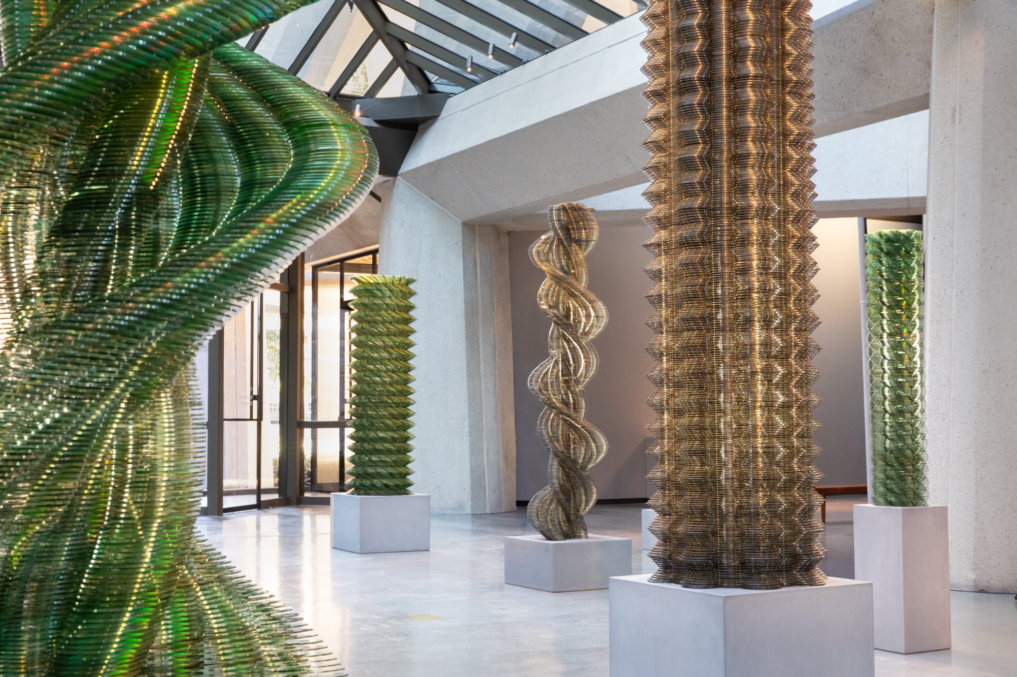 An installation view of towering artworks by Tara Donovan made of thousands of stacked CDs.