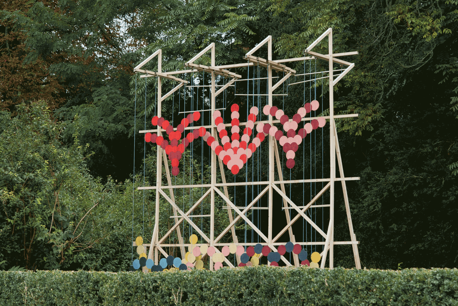 A gif of a kinetic installation by Pinaffo & Pluvinage of colorful discs that move in patterns across the front of a slender scaffold.