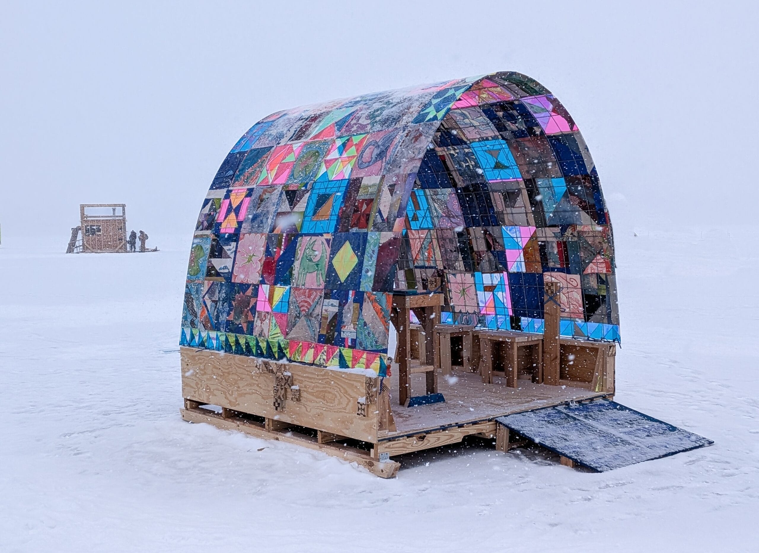 A patchwork artwork titled "Quilt Shanty" that creates an artistic winter shelter on the ice in the style of an ice fishing shanty