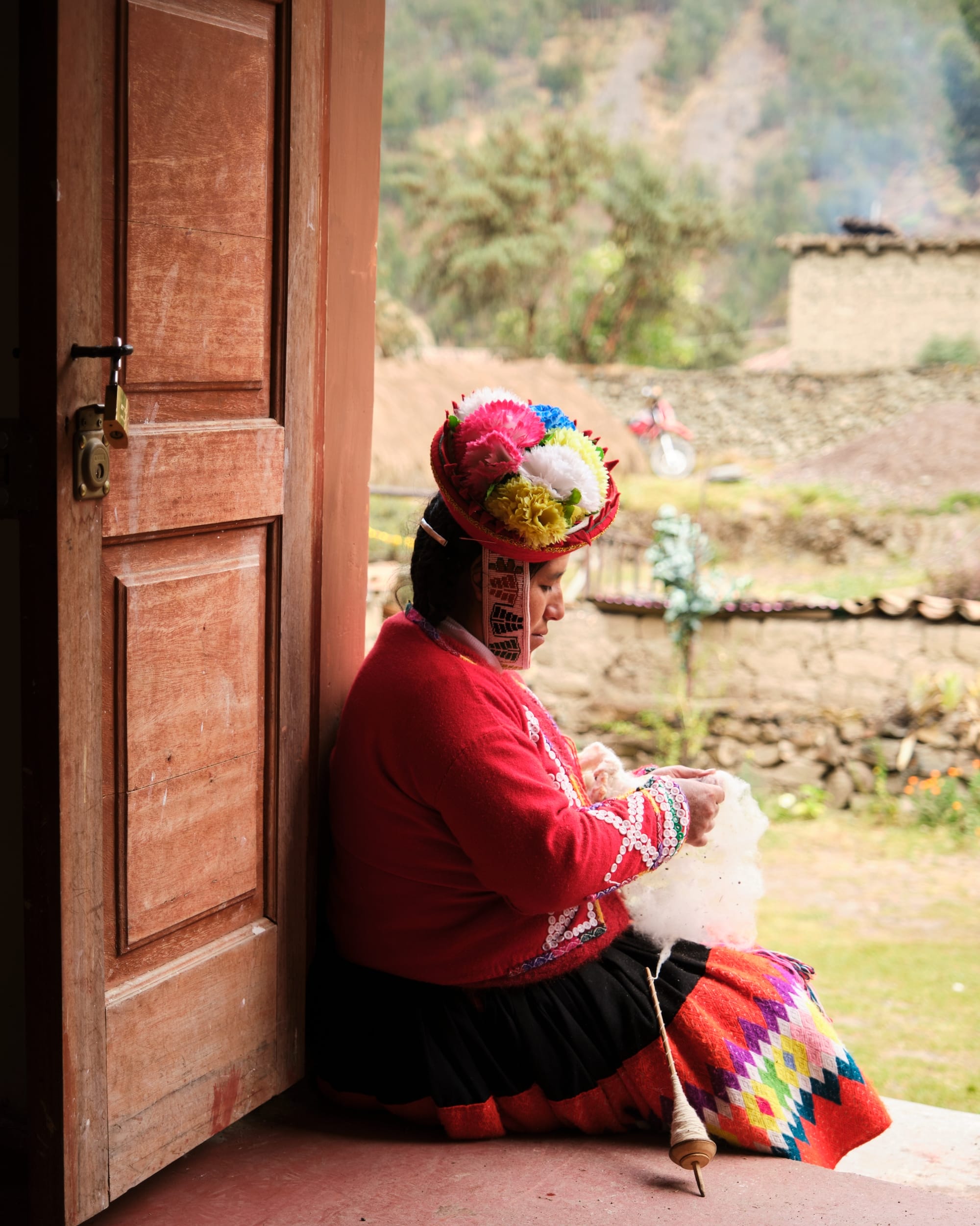 a woman in traditional Peruvian clothing sitting in a doorway