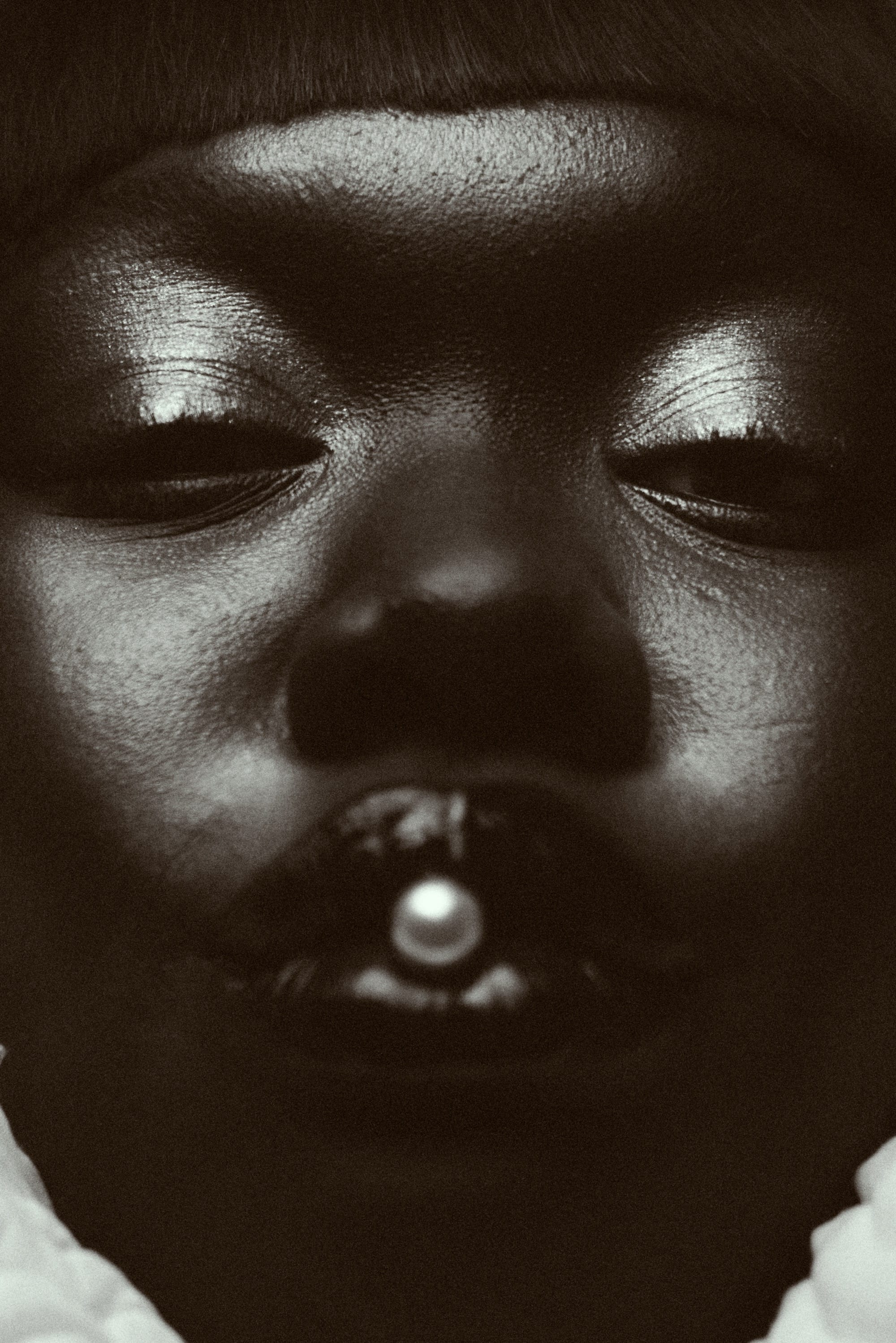 a black and white photo by Austn Fischer of a woman with a pearl in her mouth