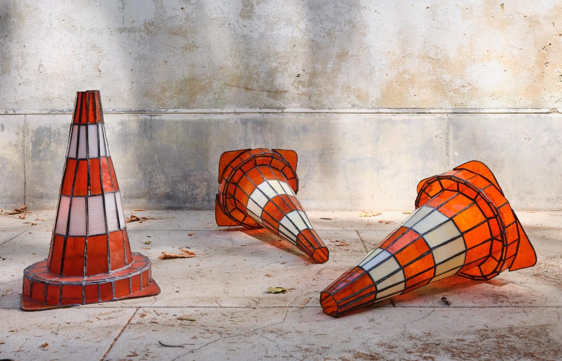 a stained glass sculpture by Pia Hinz of three traffic cones on the sidewalk