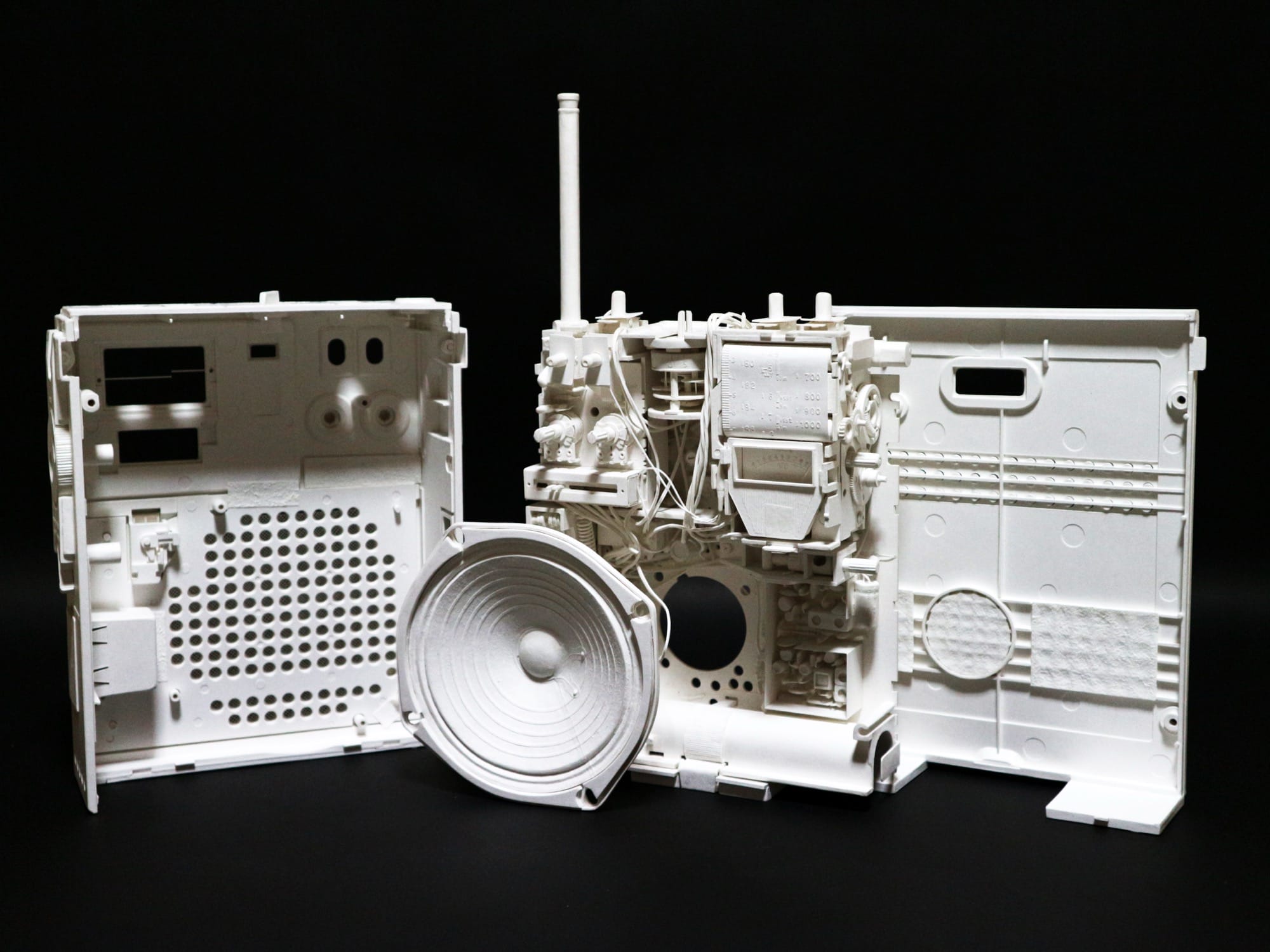 a hyperrealistic, scale sculpture of a small radio made from white paper, deconstructed to show its inner parts