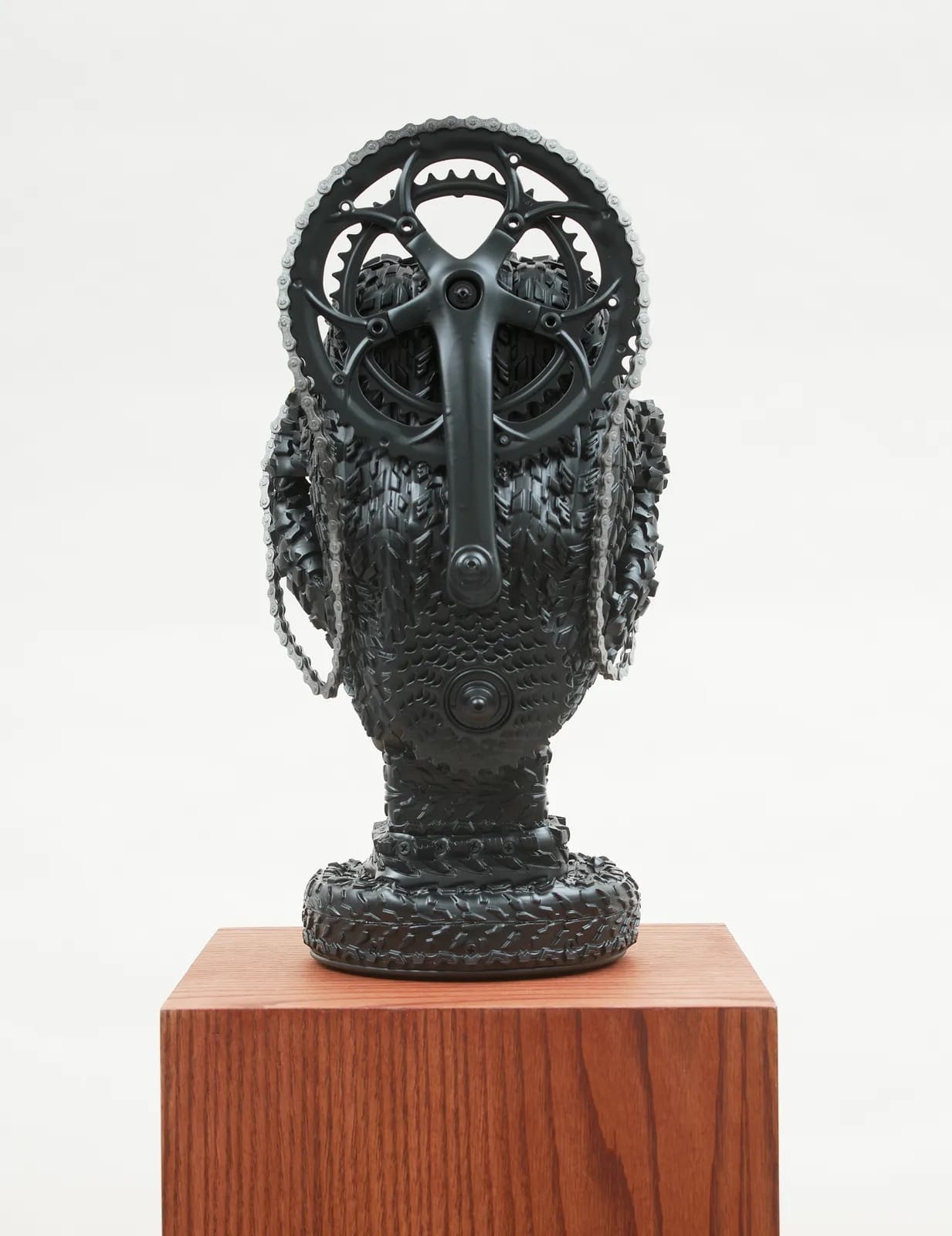 a bike tire bust by Kim Dacres of a woman with a gear and bike chains hanging across her face and head