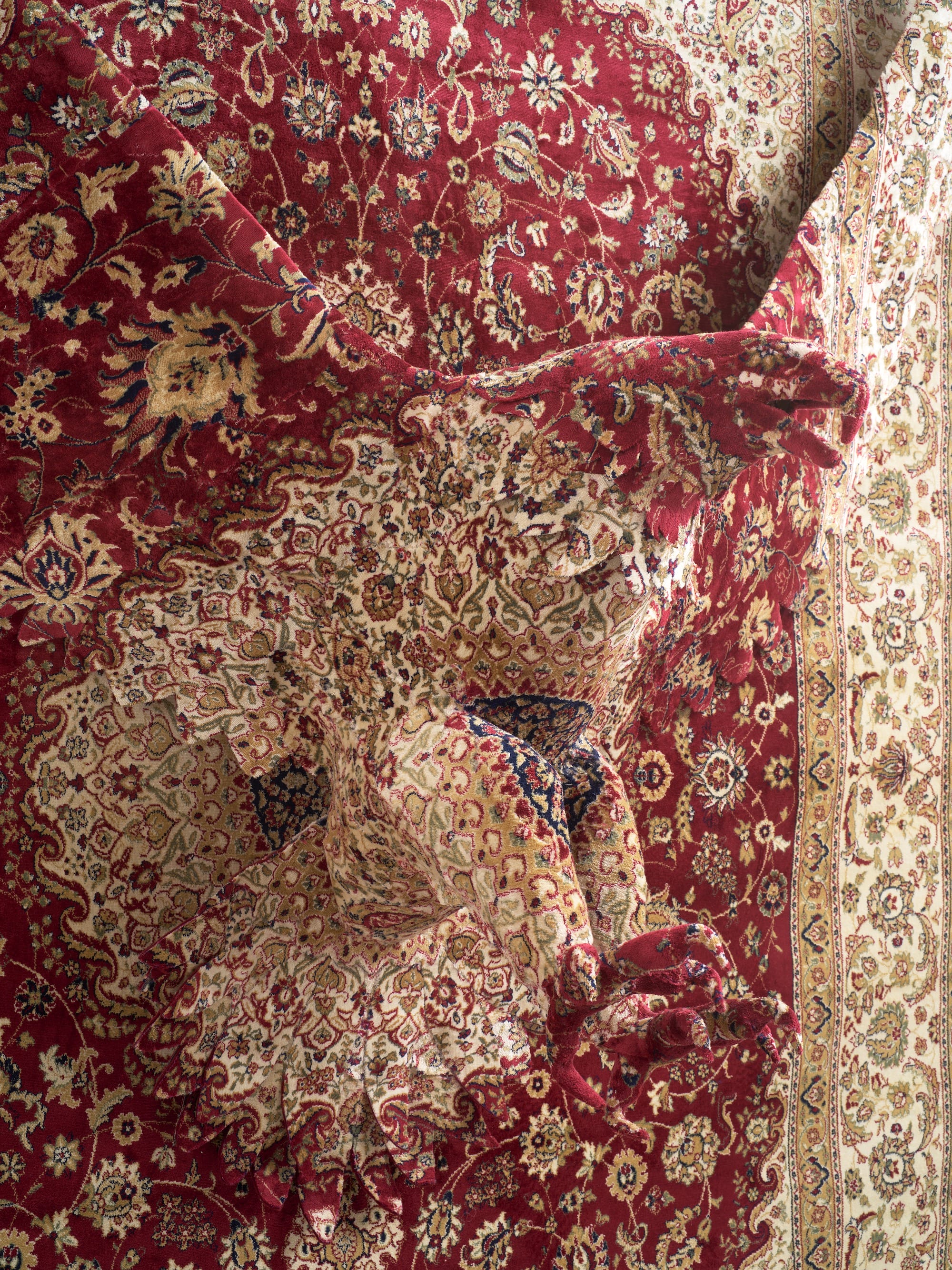 a detail of a large wall sculpture by Debbie Lawson made from ornamental woven carpet, with the silhouette of an eagle flying out of the center