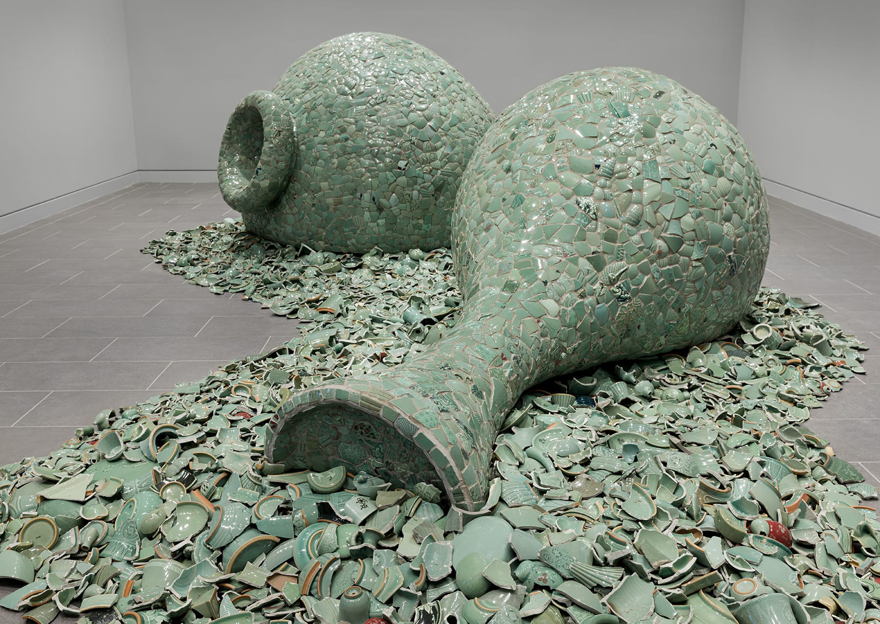 two large vessels on the floor of mosaiced celadon fragments that cloak the forms and spill out into a pool