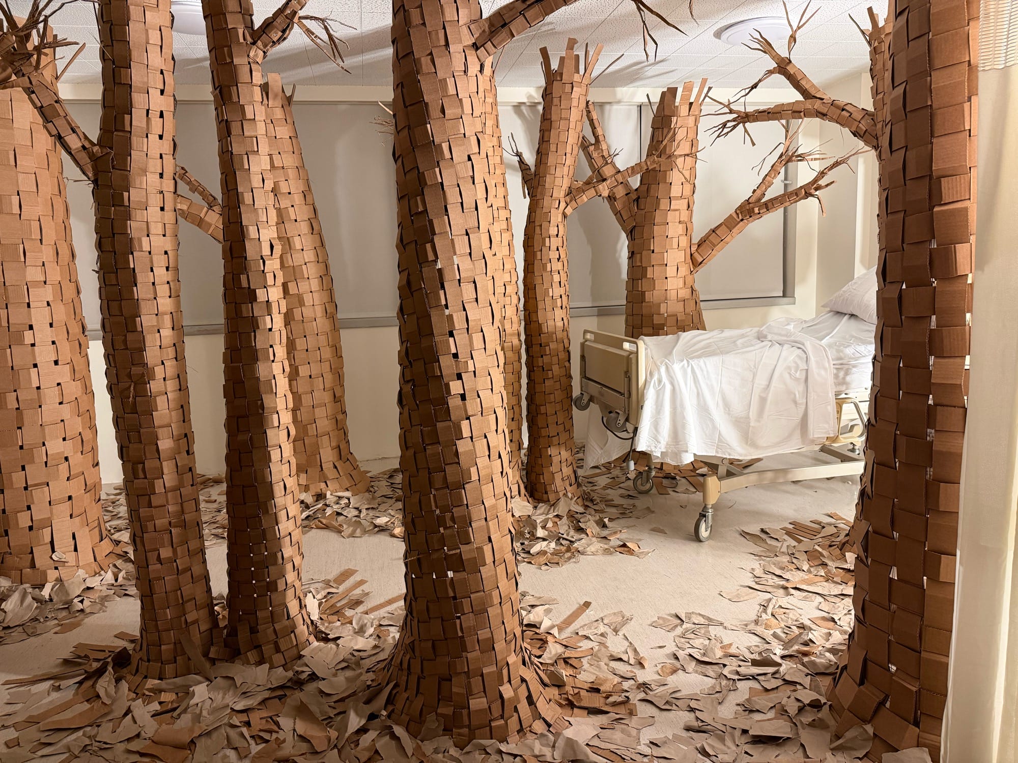 a hospital room installation transformed by large paper trees