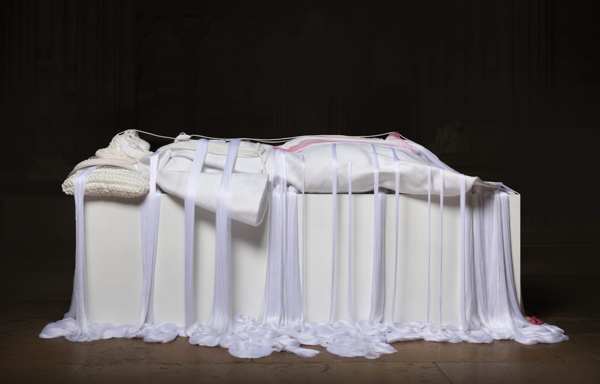 a mixed media white rope sculpture of a female figure laying down, referencing noble sculptures on top of sarcophagi, with draping ropes pooling at the floor